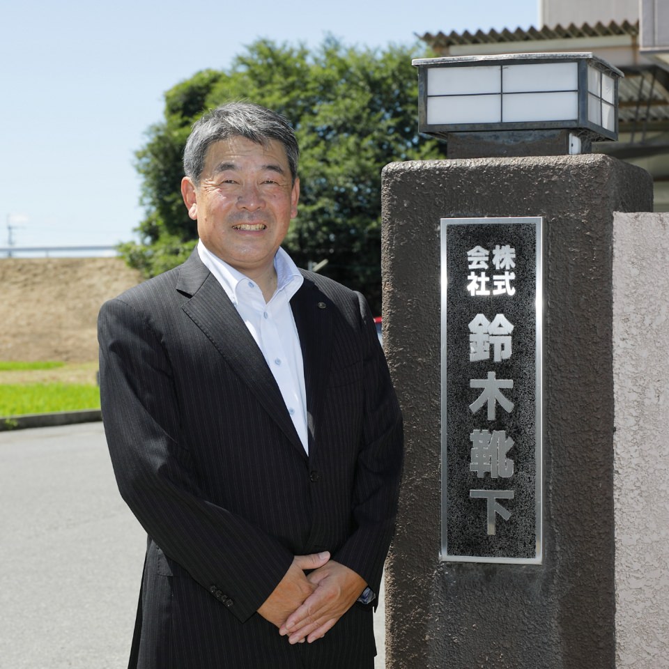 本社前に立つ鈴木靴下の代表取締役