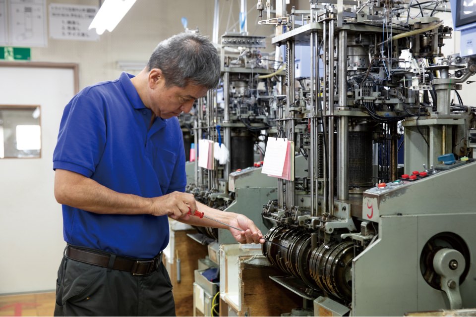 工具を持って機械のメンテナンスを行う技術者