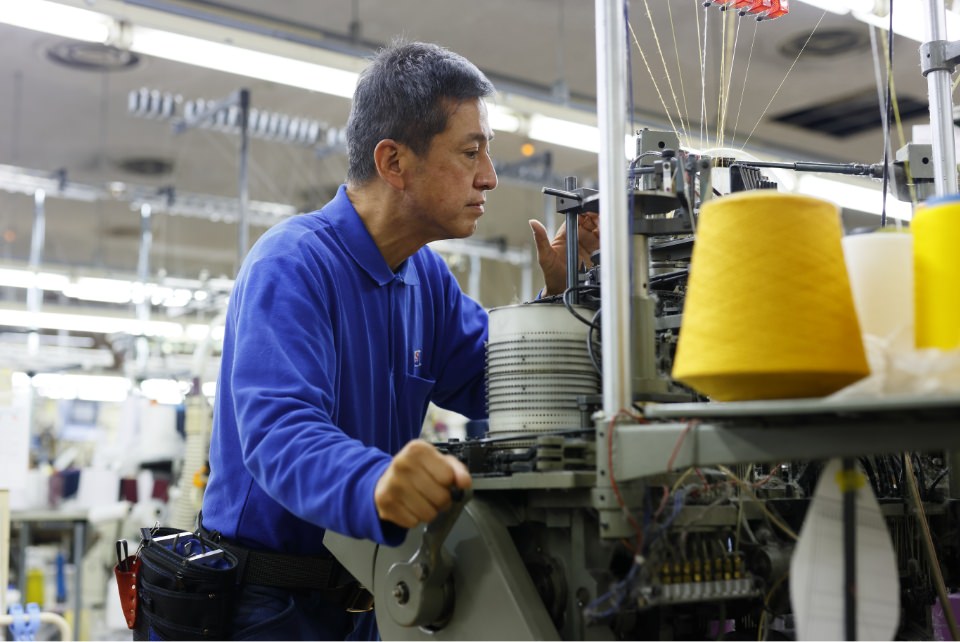 工場で編み機を操作する作業員