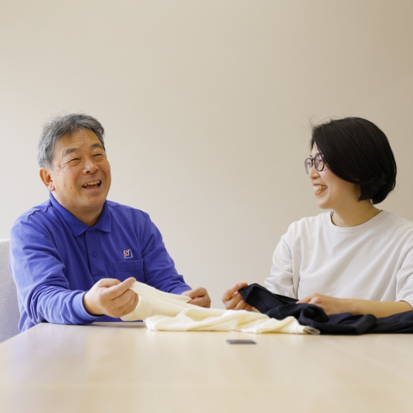 靴下生地を手に取りながら会話する男性と女性