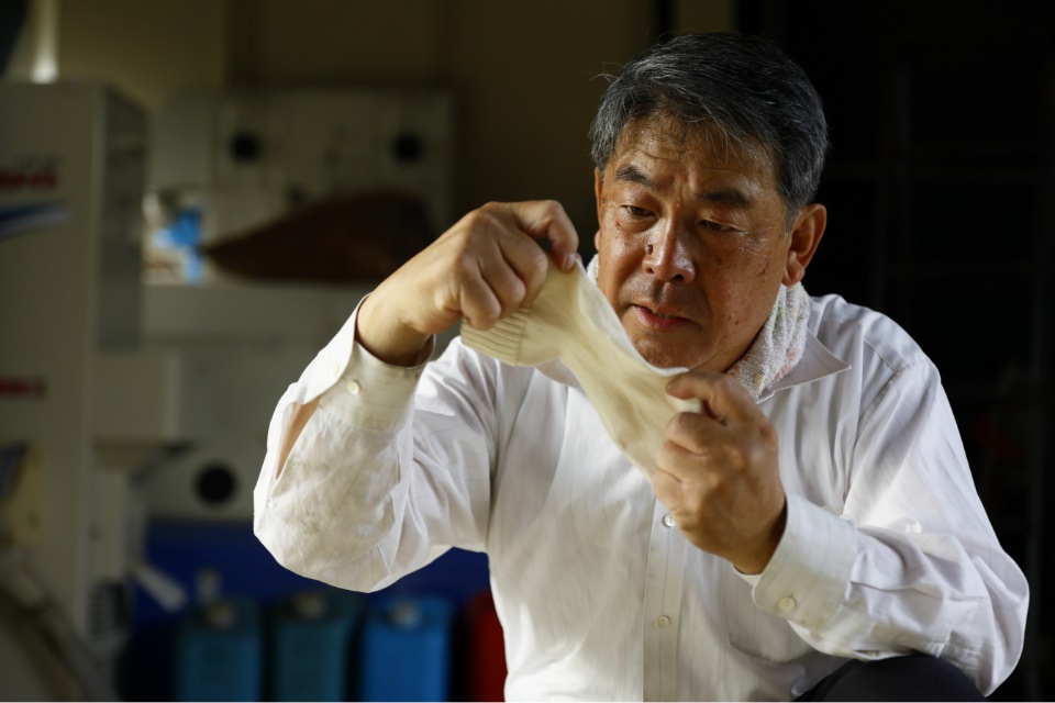 靴下を手に持って引き延ばす鈴木靴下代表