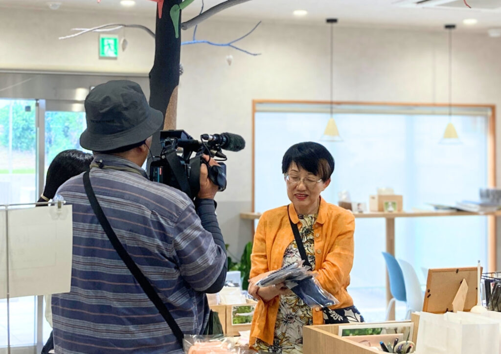 鈴木靴下直営店で行われたテレビ番組の収録で、カメラの前で取材を受けるお客様。