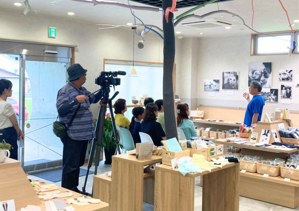 鈴木靴下直営店で、お客様に向けて靴下づくりや商品開発について話す社長・鈴木和夫。
