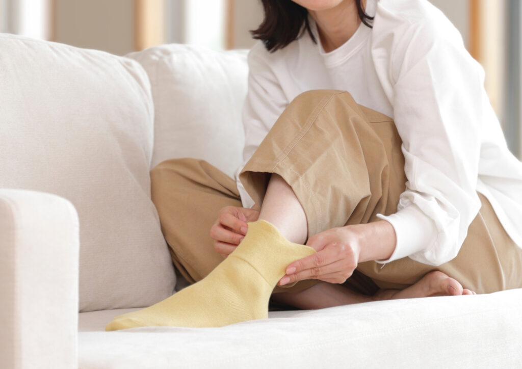 自然な暮らしの中で靴下を履く女性の足元