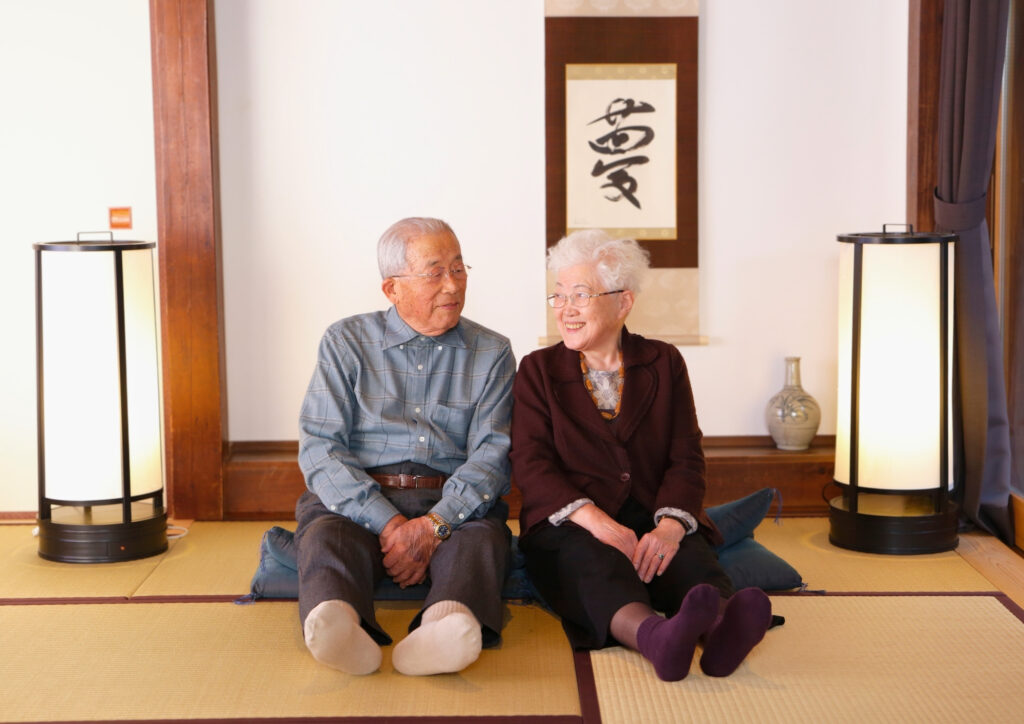 鈴木靴下の創業者と妻が畳の部屋で向かい合って微笑む様子